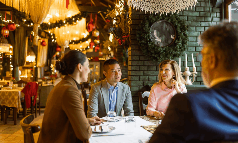 Group of people sitting at a table in an inn or restaurant decorated for the holiday season